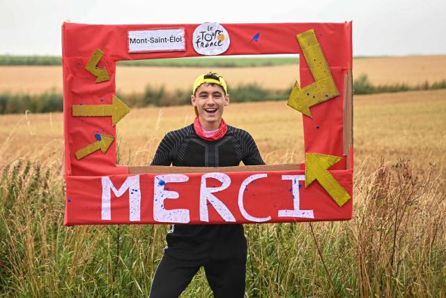 A spectator holds a placard along the race route during the 2nd stage of the 112th edition of the Tour de France cycling race, 209.1 km between Lauwin-Planque and Boulogne-sur-Mer, Northern France, on July 6, 2025. (Photo by Loic VENANCE / AFP)