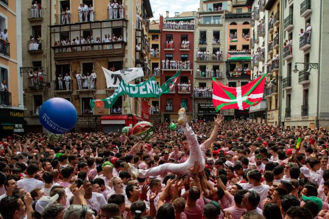 Revellers celebrate during the "Chupinazo" (rocket launch) marking the official start of the San Fermin Festival in Plaza Consistorial outside the Town Hall of Pamplona in northern Spain on July 6, 2025. Thousands of people every year attend the week-long festival and its famous 'encierros' (bull runs) in which six bulls are released at 8:00 a.m. evey day starting July 7, to run from their corral to the bullring through the narrow streets of the old town over an 850 meters (yard) course while runners ahead of them try to stay close to the bulls without falling over or being gored. (Photo by JORGE GUERRERO / AFP)