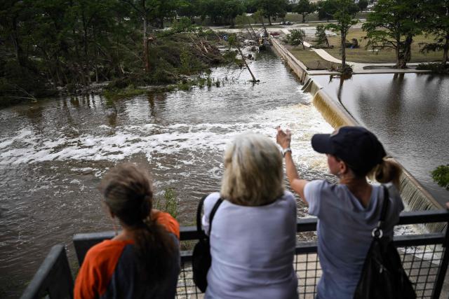 Women look at the Guadalupe River in Kerrville, Texas, on July 6, 2025, following severe flash flooding that occured during the July 4 holiday weekend. Rescuers in Texas raced against time Sunday to find dozens of missing people, including children, swept away by flash floods that killed at least 78, as forecasters warned of new deluges. Local Texans joined forces with disaster officials to search through the night for the missing, including 27 girls from a riverside Christian summer camp. Texas Governor Greg Abbott said Camp Mystic on the banks of the Guadalupe River, where some 750 girls had been staying when the floodwaters hit, had been "horrendously ravaged in ways unlike I've seen in any natural disaster." (Photo by RONALDO SCHEMIDT / AFP)