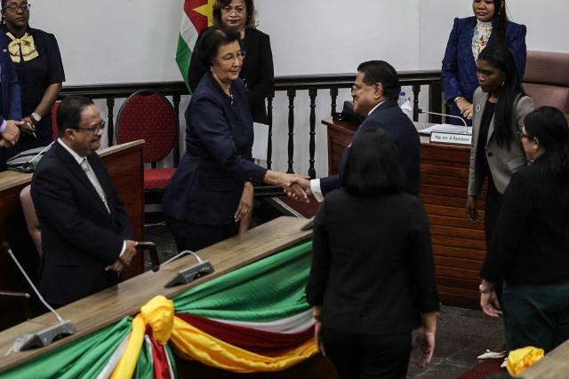 Suriname's opposition leader Jennifer Geerlings-Simons (C-L) shakes hands with the outgoing President Chan Santokhi (C-R) after the National Assembly election in Paramaribo on July 6, 2025. Lawmakers elected Jennifer Geerlings-Simons as Suriname's first woman president on July 6, 2025, after her party won the most seats in legislative elections in May. (Photo by Ranu Abhelakh / AFP)