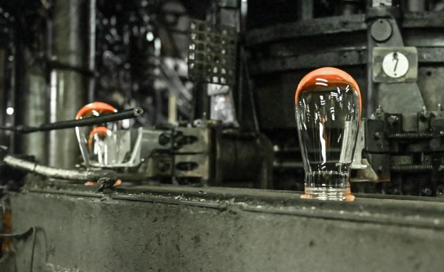 (FILES) This photograph shows glasses coming out of a furnance at the factory of the Arc International company, specialised in the design and the manufacture of table glassware, in Arques on September 13, 2022. In its industrial cathedral in northern France, glassmaker Arc International is relying on restructuring and new shareholders to overcome its difficulties, while also seeking to reduce its carbon emissions. (Photo by DENIS CHARLET / AFP)