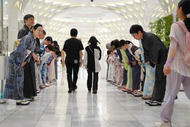 Sales clerks of the Nihonbashi Mitsukoshi department store clad in yukata, a Japanese unlined cotton summer kimono dress, greet customers in Tokyo on July 7, 2025. (Photo by Kazuhiro NOGI / AFP)