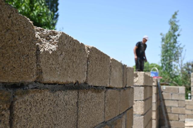 Workers build a house with rice construction blocks, made mostly of rice husks - a byproduct of rice processing, in the Kyzyl-Kiya village in southern Kyrgyzstan on May 22, 2025. (Photo by Guliza Urustambek kyzy / AFP)