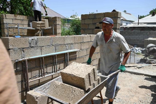 Workers build a house with rice construction blocks, made mostly of rice husks - a byproduct of rice processing, in the Kyzyl-Kiya village in southern Kyrgyzstan on May 22, 2025. (Photo by Guliza Urustambek kyzy / AFP)