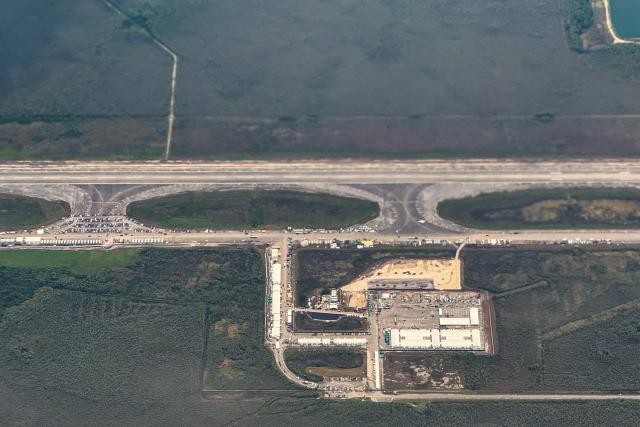 An ariel view of a migrant detention center, dubbed "Alligator Alcatraz," is seen located at the site of the Dade-Collier Training and Transition Airport in Ochopee, Florida on July 7, 2025. The $450 million camp has been built on a disused airfield deep in the Florida Everglades and is surrounded by swamps that are home to creatures including alligators and poisonous snakes. The steaming hot, mosquito-infested site is a symbol of the Republican administration's determination to look tough as it pursues its policy of mass deportations of undocumented migrants. (Photo by CHANDAN KHANNA / AFP)