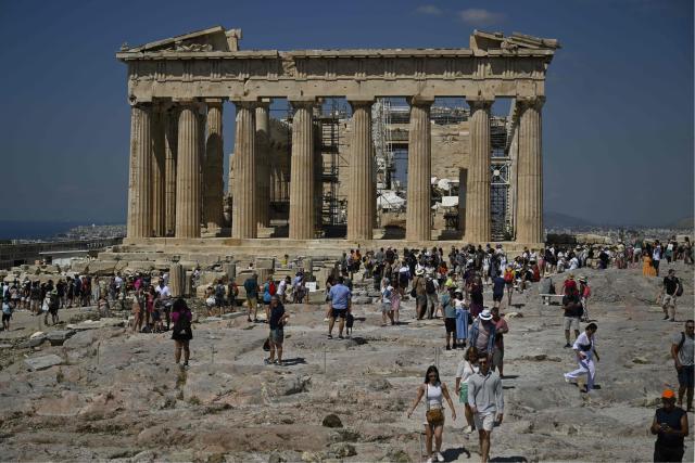 (FILES) Tourists walk in front of the Parthenon Temple as they visit the Acropolis archaeological site in Athens on June 14, 2023. Greece's culture ministry on July 8, 2025, ordered a partial closure of the Acropolis, the country's top monument, to protect visitors amid heatwave conditions. The ministry in a statement said the site would be closed from 1:00 to 5:00 pm (1000 to 1400 GMT) "for the safety of workers and visitors, owing to high temperatures." (Photo by Louisa GOULIAMAKI / AFP)