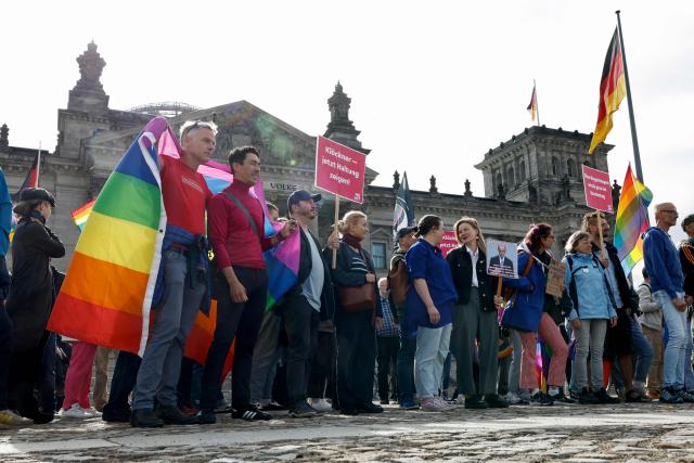 Demonstrators with rainbow flags protest in an LGBTQ+ action titled "Show the flag: For queer visibility in the Bundestag!" on July 8, 2025 in front of the Reichstag building that houses the Bundestag (lower house of parliament) in Berlin, prior to a general debate at the parliament and ahead of the Christopher Street Day (CSD) pride march to take place on July 26, 2025 in the German capital. (Photo by Odd ANDERSEN / AFP)