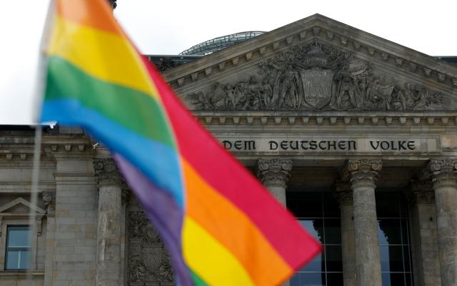 A rainbow flag is seen in front of the Reichstag building that houses the Bundestag (lower house of parliament) as demonstrators protest in an LGBTQ+ action titled "Show the flag: For queer visibility in the Bundestag!" on July 8, 2025 in Berlin, prior to a general debate at the parliament and ahead of the Christopher Street Day (CSD) pride march to take place on July 26, 2025 in the German capital. (Photo by Odd ANDERSEN / AFP)