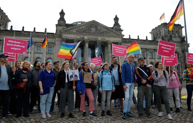 Demonstrators with rainbow flags protest in an LGBTQ+ action titled "Show the flag: For queer visibility in the Bundestag!" on July 8, 2025 in front of the Reichstag building that houses the Bundestag (lower house of parliament) in Berlin, prior to a general debate at the parliament and ahead of the Christopher Street Day (CSD) pride march to take place on July 26, 2025 in the German capital. (Photo by Odd ANDERSEN / AFP)