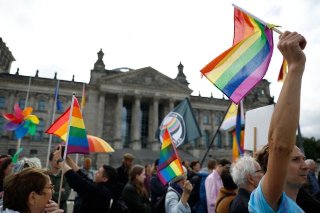 Demonstrators with rainbow flags protest in an LGBTQ+ action titled "Show the flag: For queer visibility in the Bundestag!" on July 8, 2025 in front of the Reichstag building that houses the Bundestag (lower house of parliament) in Berlin, prior to a general debate at the parliament and ahead of the Christopher Street Day (CSD) pride march to take place on July 26, 2025 in the German capital. (Photo by Odd ANDERSEN / AFP)