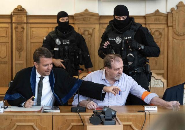 Defendant Juraj Cintula (R), a 72-year-old poet, passes a cup of water to his lawyer Namir Alyastry (L) in the courtroom in Banska Bystrica, Slovakia, on July 8, 2025, before the start of his trial where he is accused of shooting Slovakia's Prime Minister Robert Fico (unseen) on May 15, 2024. The man who admitted to shooting Slovak Prime Minister Robert Fico is due to stand trial on terror charges on July 7, 2025 in the central Slovak city of Banska Bystrica, more than a year after the attack shocked the central European country. Detained at the scene, Juraj Cintula, a 72-year-old poet, who has admitted to shooting the leader with the intention to wound but not kill him, is facing up to life in prison if convicted. (Photo by Joe Klamar / AFP)