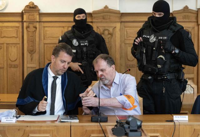 Defendant Juraj Cintula (R), a 72-year-old poet, passes a cup of water to his lawyer Namir Alyastry (L) in the courtroom in Banska Bystrica, Slovakia, on July 8, 2025, before the start of his trial where he is accused of shooting Slovakia's Prime Minister Robert Fico (unseen) on May 15, 2024. The man who admitted to shooting Slovak Prime Minister Robert Fico is due to stand trial on terror charges on July 7, 2025 in the central Slovak city of Banska Bystrica, more than a year after the attack shocked the central European country. Detained at the scene, Juraj Cintula, a 72-year-old poet, who has admitted to shooting the leader with the intention to wound but not kill him, is facing up to life in prison if convicted. (Photo by Joe Klamar / AFP)