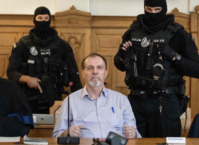 TOPSHOT - Defendant Juraj Cintula, a 72-year-old poet, sits guarded by two police officers in the courtroom in Banska Bystrica, Slovakia, on July 8, 2025, before the start of his trial where he is accused of shooting Slovakia's Prime Minister Robert Fico (unseen) on May 15, 2024. The man who admitted to shooting Slovak Prime Minister Robert Fico is due to stand trial on terror charges on July 7, 2025 in the central Slovak city of Banska Bystrica, more than a year after the attack shocked the central European country. Detained at the scene, Juraj Cintula, a 72-year-old poet, who has admitted to shooting the leader with the intention to wound but not kill him, is facing up to life in prison if convicted. (Photo by Joe Klamar / AFP)