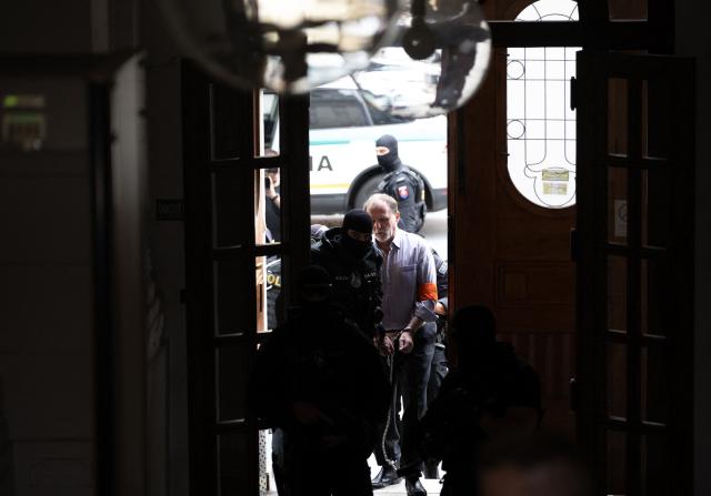 Police escort Juraj Cintula (R), a 72-year-old poet, into the courtroom in Banska Bystrica, Slovakia, on July 8, 2025, for the start of his trial where he is accused of shooting Slovakia's Prime Minister Robert Fico (unseen) on May 15, 2024. The man who admitted to shooting Slovak Prime Minister Robert Fico is due to stand trial on terror charges on July 7, 2025 in the central Slovak city of Banska Bystrica, more than a year after the attack shocked the central European country. Detained at the scene, Juraj Cintula, a 72-year-old poet, who has admitted to shooting the leader with the intention to wound but not kill him, is facing up to life in prison if convicted. (Photo by Joe Klamar / AFP)