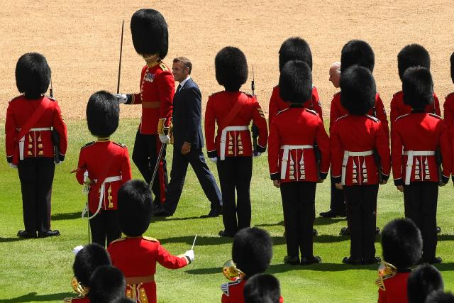 Britain's King Charles III (R) and France's President Emmanuel Macron (C) inspect a Guard of Honour during a ceremonial welcome at Windsor Castle, in Windsor west of London, on July 8, 2025, on the first day of a three-day state visit to Britain. French President Emmanuel Macron began a three-day state visit to Britain on Tuesday, which will see him address parliament and try to rekindle a purportedly warm relationship with King Charles III. (Photo by Jaimi Joy / POOL / AFP)