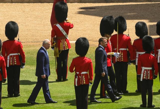 Britain's King Charles III (L) and France's President Emmanuel Macron inspect a Guard of Honour during a ceremonial welcome at Windsor Castle, in Windsor west of London, on July 8, 2025, on the first day of a three-day state visit to Britain. French President Emmanuel Macron began a three-day state visit to Britain on Tuesday, which will see him address parliament and try to rekindle a purportedly warm relationship with King Charles III. (Photo by Jaimi Joy / POOL / AFP)