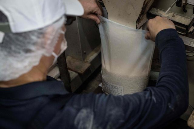 A member of staff packs rice for export to the US at a rice store in Tokyo on July 9, 2025. While US President Donald Trump imposed a 10 percent tariff on most US trading partners in April, the rate is set to rise for dozens of economies including the European Union and Japan come July 9. (Photo by Yuichi YAMAZAKI / AFP)