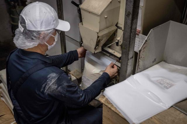A member of staff packs rice for export to the US at a rice store in Tokyo on July 9, 2025. While US President Donald Trump imposed a 10 percent tariff on most US trading partners in April, the rate is set to rise for dozens of economies including the European Union and Japan come July 9. (Photo by Yuichi YAMAZAKI / AFP)