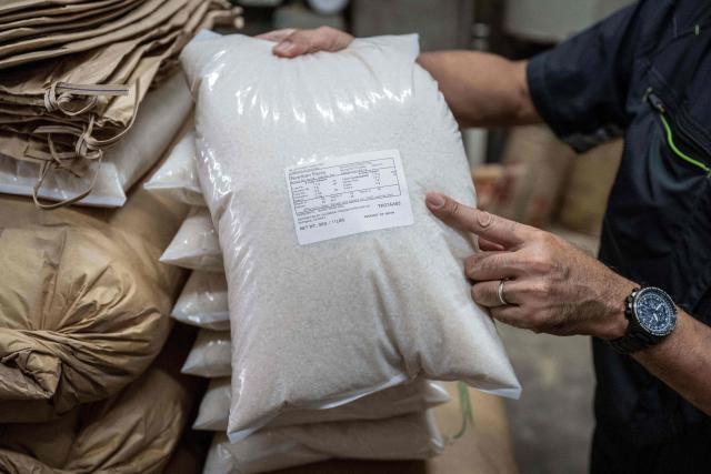 A member of staff shows a bag of rice for export to the US at a rice store in Tokyo on July 9, 2025. While US President Donald Trump imposed a 10 percent tariff on most US trading partners in April, the rate is set to rise for dozens of economies including the European Union and Japan come July 9. (Photo by Yuichi YAMAZAKI / AFP)