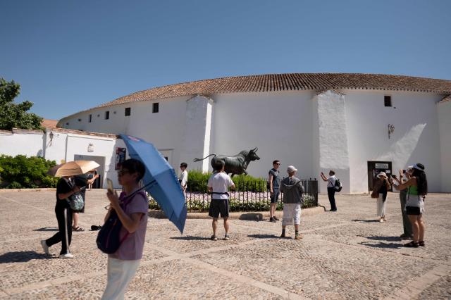 (FILES) Tourists shield from the sun with umbrellas in Ronda, southern Spain during the first heatwave of the summer, on July 2, 2025. Human-caused climate change made the recent European heatwave up to 4C hotter in many cities, scientists said on July 9, 2025, pushing temperatures into deadly territory for thousands of vulnerable people. (Photo by JORGE GUERRERO / AFP)