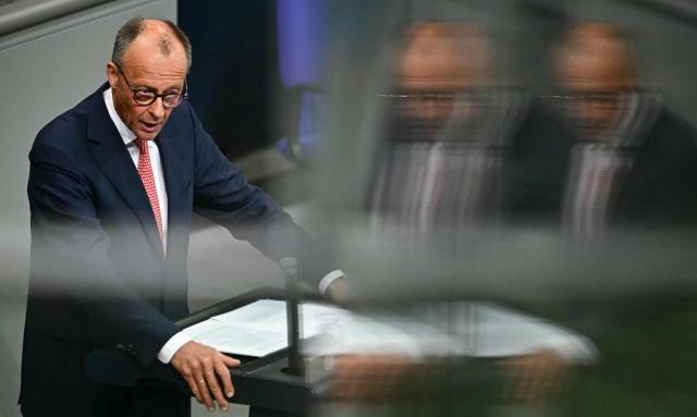 German Chancellor Friedrich Merz is reflected in a balustrade as he addresses parliamentarians during a general debate on the budget of the Chancellery at the Bundestag, the lower house of parliament, in Berlin, on July 9, 2025, while the . (Photo by Tobias SCHWARZ / AFP)