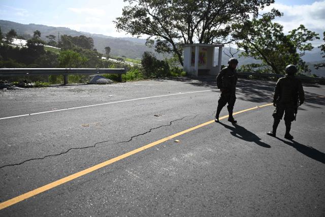 Soldiers stand by a cracked road after a series of earthquakes in Santa Maria de Jesus, Guatemala, on July 9, 2025. Two people were killed when their vehicle was buried under a landslide after a series of earthquakes shook much of the Central American country on Tuesday, Guatemalan authorities said. (Photo by JOHAN ORDONEZ / AFP)