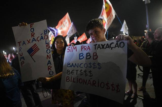 People attend a demonstration calling to tax the super-rich and demanding the end of the six-day workweek in Rio de Janeiro, Brazil, on July 10, 2025. The reduction of the workweek to six days started as a popular demand and is now gaining support among politicians. Additionally, the Brazilian federal government has presented a bill proposing a 10% tax on the super-rich, which is currently under discussion in Congress. (Photo by MAURO PIMENTEL / AFP)