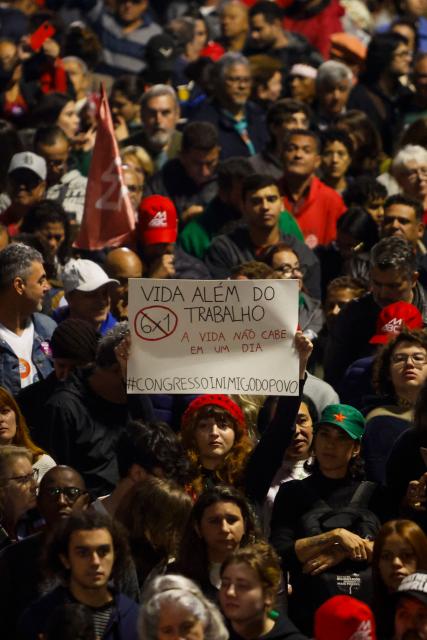 People attend a demonstration calling to tax the super-rich and demanding the end of the six-day workweek at the Paulista Avenue in Sao Paulo, Brazil, on July 10, 2025. The reduction of the workweek to six days started as a popular demand and is now gaining support among politicians. Additionally, the Brazilian federal government has presented a bill proposing a 10% tax on the super-rich, which is currently under discussion in Congress. (Photo by Miguel SCHINCARIOL / AFP)