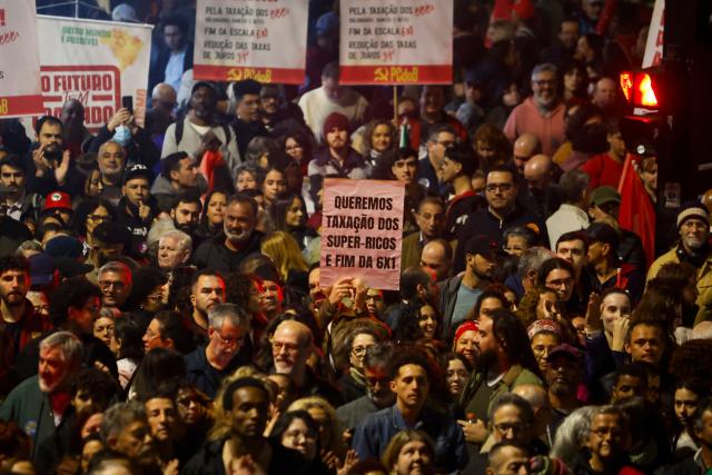 People attend a demonstration calling to tax the super-rich and demanding the end of the six-day workweek at the Paulista Avenue in Sao Paulo, Brazil, on July 10, 2025. The reduction of the workweek to six days started as a popular demand and is now gaining support among politicians. Additionally, the Brazilian federal government has presented a bill proposing a 10% tax on the super-rich, which is currently under discussion in Congress. (Photo by Miguel SCHINCARIOL / AFP)