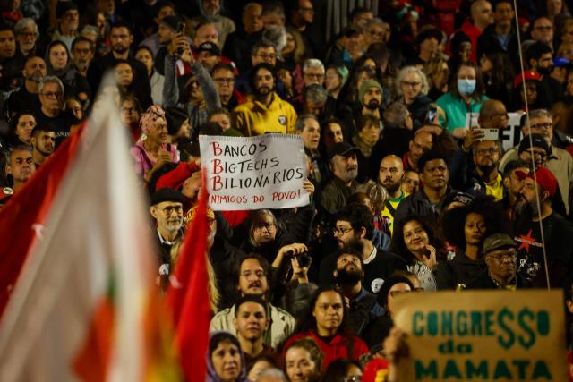 People attend a demonstration calling to tax the super-rich and demanding the end of the six-day workweek at the Paulista Avenue in Sao Paulo, Brazil, on July 10, 2025. The reduction of the workweek to six days started as a popular demand and is now gaining support among politicians. Additionally, the Brazilian federal government has presented a bill proposing a 10% tax on the super-rich, which is currently under discussion in Congress. (Photo by Miguel SCHINCARIOL / AFP)