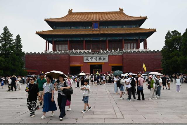 Tourists walk outside the Forbiden City in Beijing on July 11, 2025. (Photo by WANG Zhao / AFP)