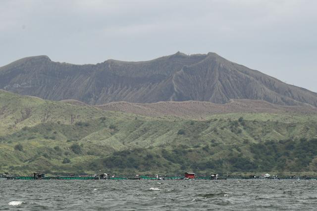 This photo shows a general view of the Taal volcano crater with fish cages (bottom) are seen along Taal Lake off Laurel town, Batangas province, south of Manila, on July 10, 2025. (Photo by Ted ALJIBE / AFP)