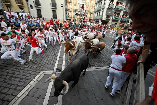 Participants run ahead of Jandilla bulls during the fifth running of the bulls of the San Fermin festival in Pamplona, northern Spain, on July 11, 2025. Thousands of people every year attend the week-long festival and its famous "encierros" or bull runs, every day at 8:00 a.m. through the narrow streets of the old town over an 850 meters (yard) course while runners ahead of them try to stay close to the bulls without falling over or being gored. (Photo by ANDER GILLENEA / AFP)
