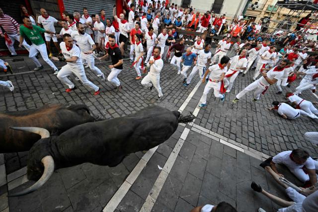 Participants run ahead of Jandilla bulls during the fifth running of the bulls of the San Fermin festival in Pamplona, northern Spain, on July 11, 2025. Thousands of people every year attend the week-long festival and its famous "encierros" or bull runs, every day at 8:00 a.m. through the narrow streets of the old town over an 850 meters (yard) course while runners ahead of them try to stay close to the bulls without falling over or being gored. (Photo by ANDER GILLENEA / AFP)