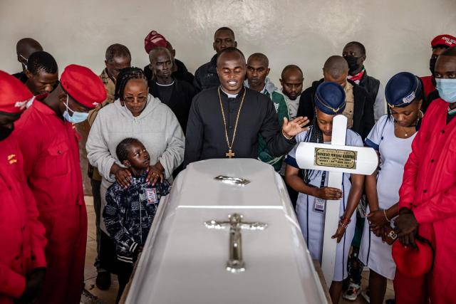 A priest leads a prayer surrounded by youth and family members in front of the casket of Boniface Kariuki, a street hawker who died from gunshot wounds days after being shot by Kenyan police during nationwide protests against police conduct and government policies, ahead of his funeral at a mortuary in Nairobi on July 11, 2025. (Photo by Luis TATO / AFP)