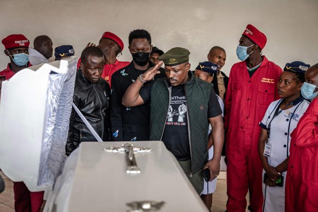 A Kenyan activist makes a salute while viewing the body of Boniface Kariuki, a street hawker who died from gunshot wounds days after being shot by Kenyan police during nationwide protests against police conduct and government policies, ahead of his funeral at a mortuary in Nairobi on July 11, 2025. (Photo by Luis TATO / AFP)