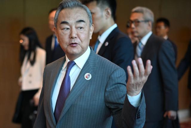 China's Foreign Minister Wang Yi gestures to the media as he walks between meetings during the 58th ASEAN Foreign Ministers’ meeting and related meetings at the Convention Centre in Kuala Lumpur on July 11, 2025. (Photo by Mandel NGAN / POOL / AFP)