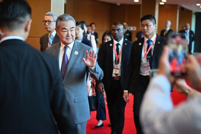 China's Foreign Minister Wang Yi (centre L) gestures to the media as he walks between meetings during the 58th ASEAN Foreign Ministers’ meeting and related meetings at the Convention Centre in Kuala Lumpur on July 11, 2025. (Photo by Mandel NGAN / POOL / AFP)