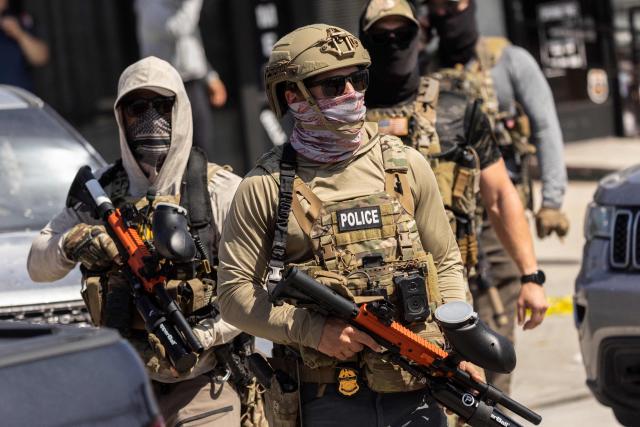 (FILES) US Custom and Border Police (CBP) officers regroup next to their vehicles as they are surrounded by community members who pushed back against their attempt to raid a store in Bell, just south of Los Angeles, California, on June 20, 2025. A federal judge on July 11 ordered the Trump administration to take measures to prevent racial profiling in Los Angeles, during the violent arrests of migrants that have been increasing in the past month around the Californian metropolis. She ruled in favor of several migrants and two American citizens, as well as the organizations that helped them file a complaint in early July. They claimed they had been victims of racial profiling and also denounced obstructions to accessing legal counsel while in detention. (Photo by ETIENNE LAURENT / AFP)