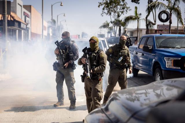 (FILES) US Custom and Border Police (CBP) officers regroup next to their vehicles as clashes erupt with community members who pushed back against their attempt to raid a store in Bell, just south of Los Angeles, California, on June 20, 2025. A federal judge on July 11 ordered the Trump administration to take measures to prevent racial profiling in Los Angeles, during the violent arrests of migrants that have been increasing in the past month around the Californian metropolis. She ruled in favor of several migrants and two American citizens, as well as the organizations that helped them file a complaint in early July. They claimed they had been victims of racial profiling and also denounced obstructions to accessing legal counsel while in detention. (Photo by ETIENNE LAURENT / AFP)