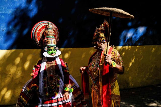 A Kathakali classical dancer (L) speaks with an artist dressed as mythological King Mahabali as they wait to perform at a cultural festival in Chennai on July 12, 2025. (Photo by R. Satish BABU / AFP)