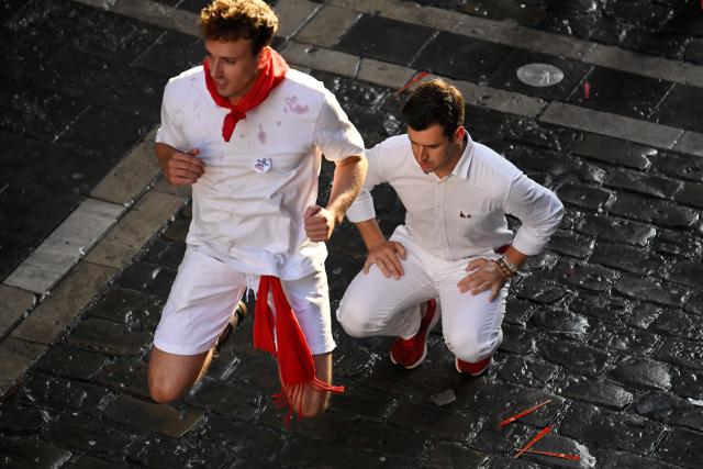 Two participants warm up before the sixth running of the bulls of the San Fermin festival in Pamplona, northern Spain, on July 12, 2025. Thousands of people every year attend the week-long festival and its famous "encierros" or bull runs, every day at 8:00 a.m. through the narrow streets of the old town over an 850 meters (yard) course while runners ahead of them try to stay close to the bulls without falling over or being gored. (Photo by MIGUEL RIOPA / AFP)