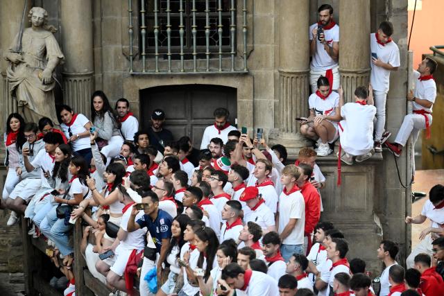 People try to find a place to watch the sixth running of the bulls of the San Fermin festival in Pamplona, northern Spain, on July 12, 2025. Thousands of people every year attend the week-long festival and its famous "encierros" or bull runs, every day at 8:00 a.m. through the narrow streets of the old town over an 850 meters (yard) course while runners ahead of them try to stay close to the bulls without falling over or being gored. (Photo by MIGUEL RIOPA / AFP)