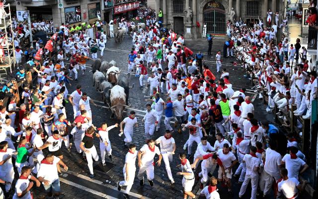 Participants run ahead of Jose Escolar breed bulls during the sixth running of the bulls of the San Fermin festival in Pamplona, northern Spain, on July 12, 2025. Thousands of people every year attend the week-long festival and its famous "encierros" or bull runs, every day at 8:00 a.m. through the narrow streets of the old town over an 850 meters (yard) course while runners ahead of them try to stay close to the bulls without falling over or being gored. (Photo by MIGUEL RIOPA / AFP)