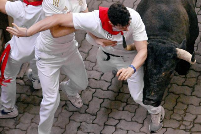 Participants try to dodge the Jose Escolar breed bulls during the sixth running of the bulls of the San Fermin festival in Pamplona, northern Spain, on July 12, 2025. Thousands of people every year attend the week-long festival and its famous "encierros" or bull runs, every day at 8:00 a.m. through the narrow streets of the old town over an 850 meters (yard) course while runners ahead of them try to stay close to the bulls without falling over or being gored. (Photo by ANDER GILLENEA / AFP)