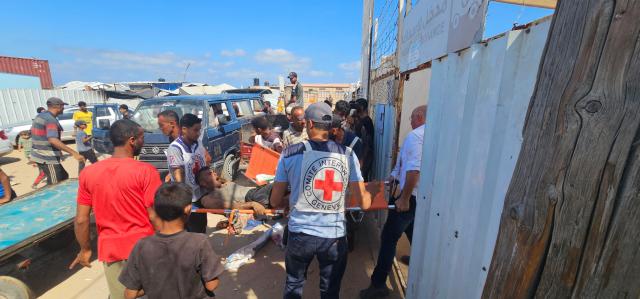 EDITORS NOTE: Graphic content / Palestinians transport a victim to a Red Cross clinic in Rafah in the southern Gaza Strip after they were reportedly shot as they waited to receive food parcels at a distribution point run by the US and Israel-backed Gaza Humanitarian Foundation (GHF), on July 12, 2025. Gaza's civil defence agency said at least 14 Palestinians were killed in the latest wave of Israeli strikes across the territory on July 12. (Photo by AFP)