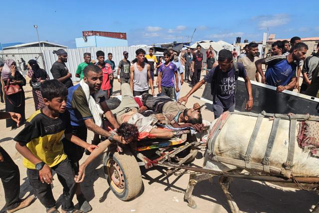 EDITORS NOTE: Graphic content / Palestinians transport victims to a Red Cross clinic in Rafah in the southern Gaza Strip after they were reportedly shot as they waited to receive food parcels at a distribution point run by the US and Israel-backed Gaza Humanitarian Foundation (GHF), on July 12, 2025. Gaza's civil defence agency said at least 14 Palestinians were killed in the latest wave of Israeli strikes across the territory on July 12. (Photo by AFP)