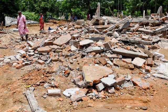 Villagers walk past the debris of their houses, demolished by local authorities during an eviction drive at an alleged illegal residential settlement inside the Paikan Reserve Forest in Goalpara district, in India’s northeastern state of Assam on July 12, 2025. (Photo by BIJU BORO / AFP)