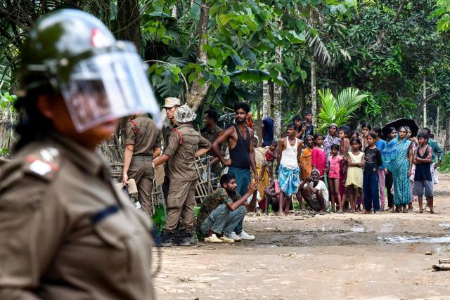 Security personnel stand guard as villagers watch the demolition of their houses by local authorities during an eviction drive at an alleged illegal residential settlement inside the Paikan Reserve Forest in Goalpara district, in India’s northeastern state of Assam on July 12, 2025. (Photo by BIJU BORO / AFP)