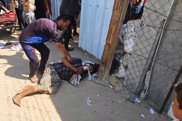 EDITORS NOTE: Graphic content / A Palestinian man helps a victim in front of a Red Cross clinic in Rafah in the southern Gaza Strip after he was reportedly shot as he waited to receive food parcels at a distribution point run by the US and Israel-backed Gaza Humanitarian Foundation (GHF), on July 12, 2025. Gaza's civil defence agency said at least 14 Palestinians were killed in the latest wave of Israeli strikes across the territory on July 12. (Photo by AFP)